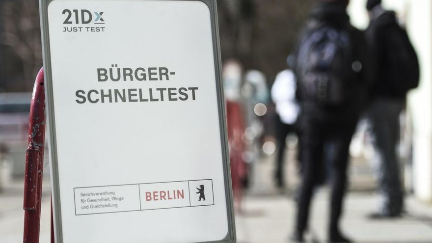 Gente hace cola frente a un centro de pruebas rápidas del coronavirus en Berlín, detrás de un cartel que dice "Prueba rápida de los ciudadanos".