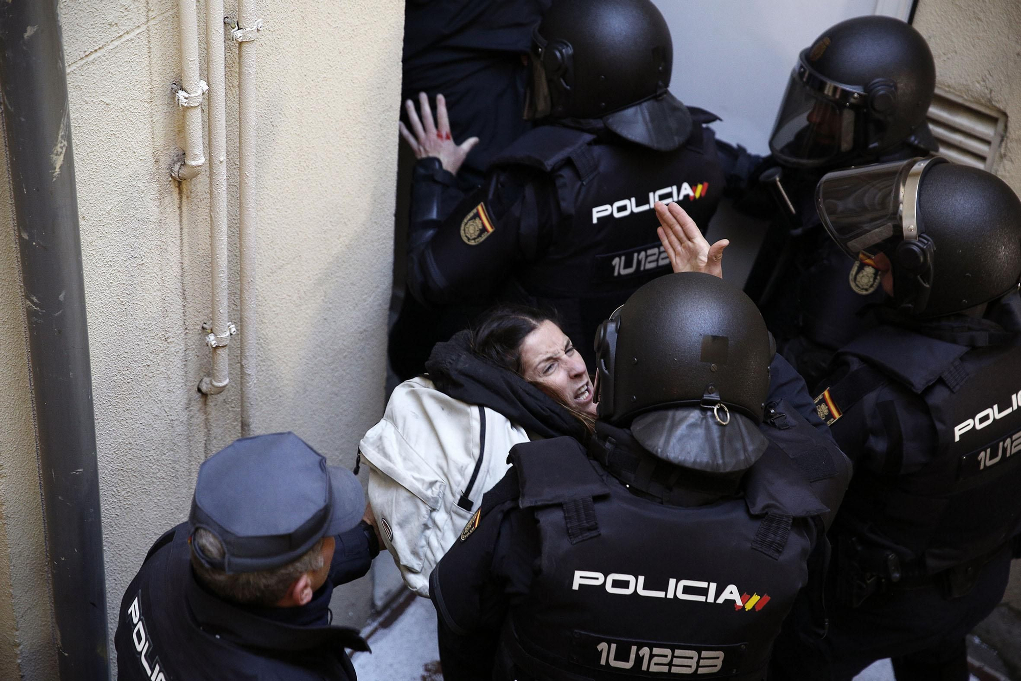 Varios policías antidisturbios sacando por la fuerza a una activista. Muchas de las personas que participaron en el intento de paralización del desahucio han asegurado que en el pasillo que se encontraba fuera del alcance de las cámaras han recibido patadas y puñetazos por parte de los policías.