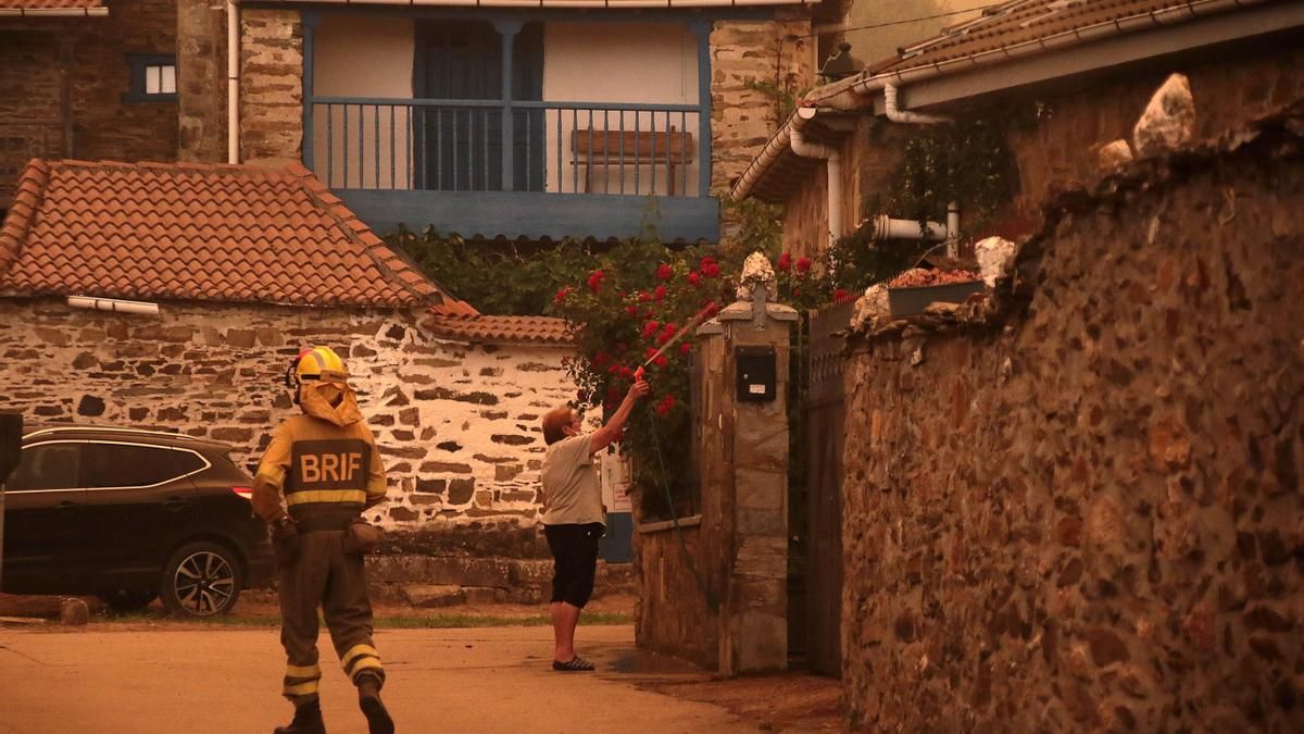Vecinos con manguera junto a personal forestal luchando contra el incendio en el municipio de Lucillo.