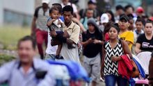 Un padre que carga a su hijo fue registrado este miércoles al caminar en medio de una caravana migrante, rumbo a la frontera guatemalteca de Agua Caliente, a su paso por San Pedro Sula (Honduras).