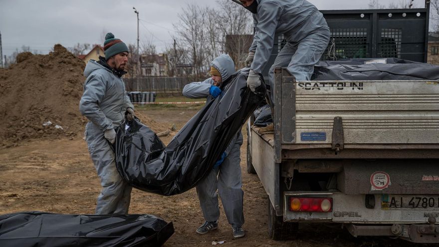Autoridades forenses recogen cadáveres envueltos en plásticos para su traslado a la morgue, en Bucha (Ucrania)