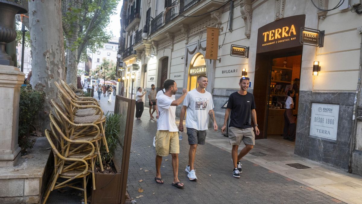 Unos jóvenes turistas pasean al lado de los residentes durante la cena al aire libre.