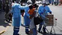 Personal de la Cruz Roja asiste a cientos de personas que esperan junto a una terminal de buses en Lima con la esperanza de poder regresar a sus lugares de origen.