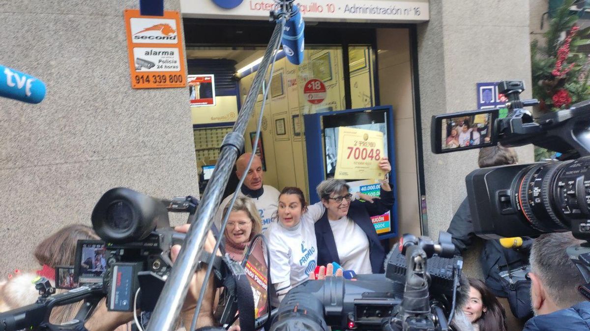 Raquel sostiene el cartel con el segundo premio de El Gordo, el 70.048, a las puertas de la Administración de Lotería.