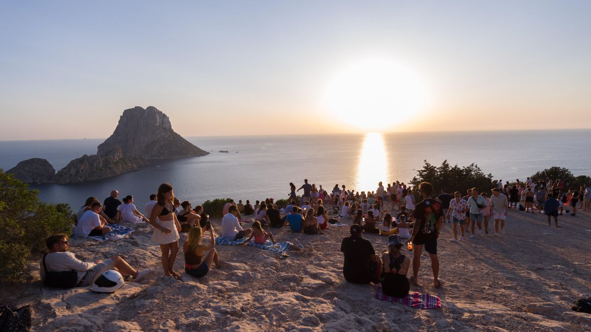 Grupos de personas disfrutan del atardecer en la Cala d'Hort.