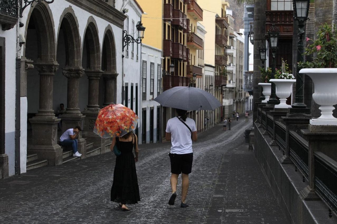 Dos personas pasean por Santa Cruz de La Palma protegidas de la caída de cenizas con sendos paraguas