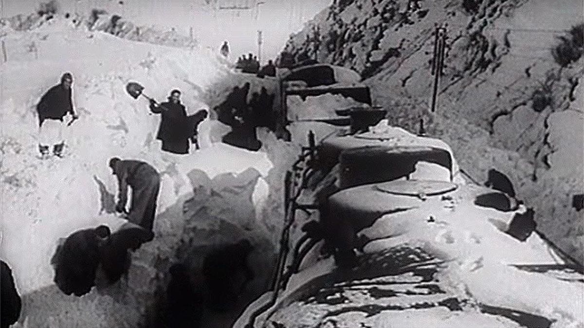 Grupo de operarios de la Renfe espalando para sacar a paladas un tren en la línea León-Asturias 1953