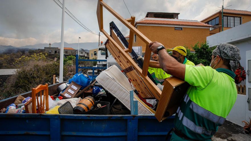 Dos hombres de mantenimiento del Ayuntamiento colaboran en recoger las pertenencias de los vecinos del núcleo urbano de Todoque durante el desalojo de sus viviendas ante la aproximación de la lava del volcán