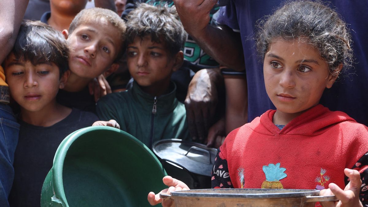 Niños y niñas palestinos aguardan en la cola de reparto de comida este fin de semana en una campamento de desplazados en Gaza