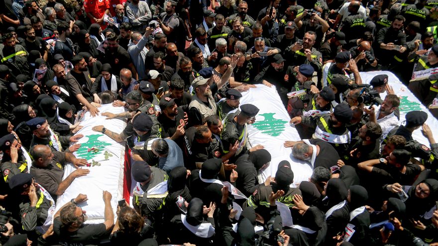 Personas alrededor de los ataúdes de tres miembros de la Defensa Civil libanesa, asesinados en un ataque israelí en la aldea de Majdal Zoun.