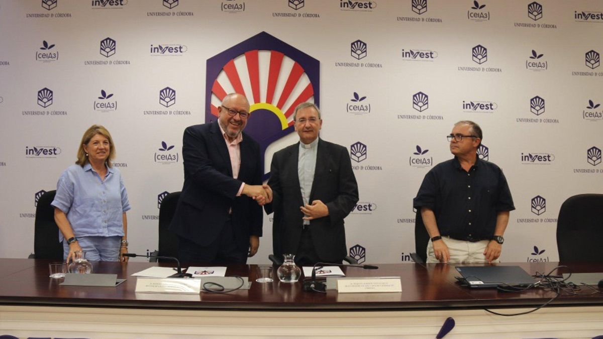 El rector y el deán estrechan sus manos tras la firma del acuerdo.