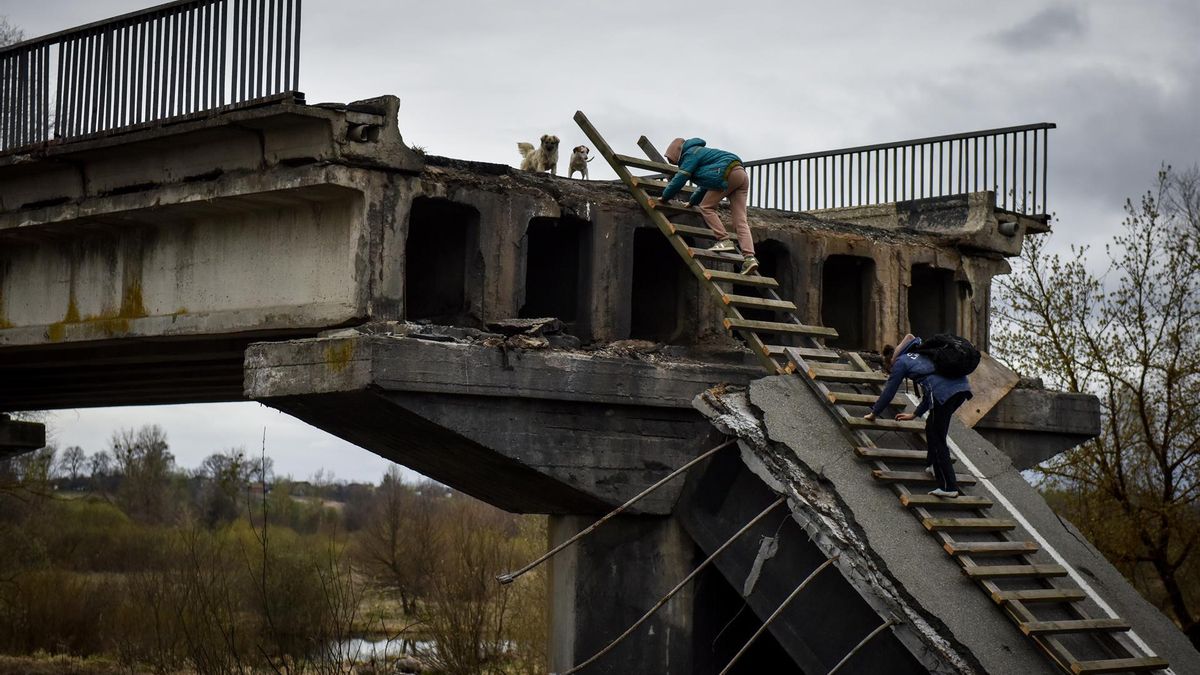 Kyiv (Ukraine), 19/04/2022.- Local citizen Natalia and her daughter climb a ladder, passing over a destroyed bridge in Kyiv (Kiev) area, Ukraine, 19 April 2022. On 24 February Russian troops had entered Ukrainian territory resulting in fighting and destruction in the country, a huge flow of refugees, and multiple sanctions against Russia. (Rusia, Ucrania)