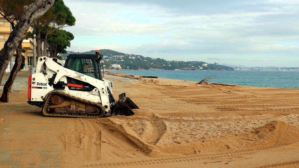 Operarios retiran la arena del paseo marítimo de Platja d'Aro, que ha quedado totalmente enterrado después del temporal