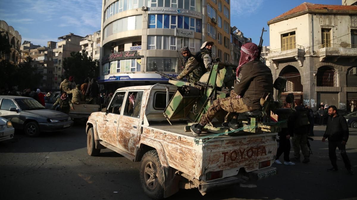 Rebeldes sirios en la parte trasera de un vehículo mientras la gente celebra en las calles de Homs, Siria, la caída del gobierno de Bachar al Asad el 8 de diciembre de 2024.