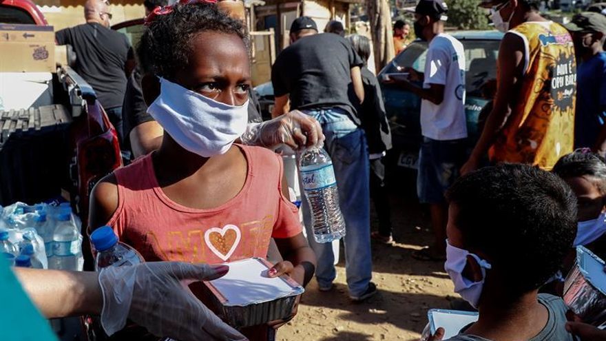 Fotografía fechada el 31 de mayo de 2020 de niños recibiendo una donación de alimentos en la comunidad de Capadócia, en Brasilandia, un barrio en la periferia de la ciudad de São Paulo (Brasil).