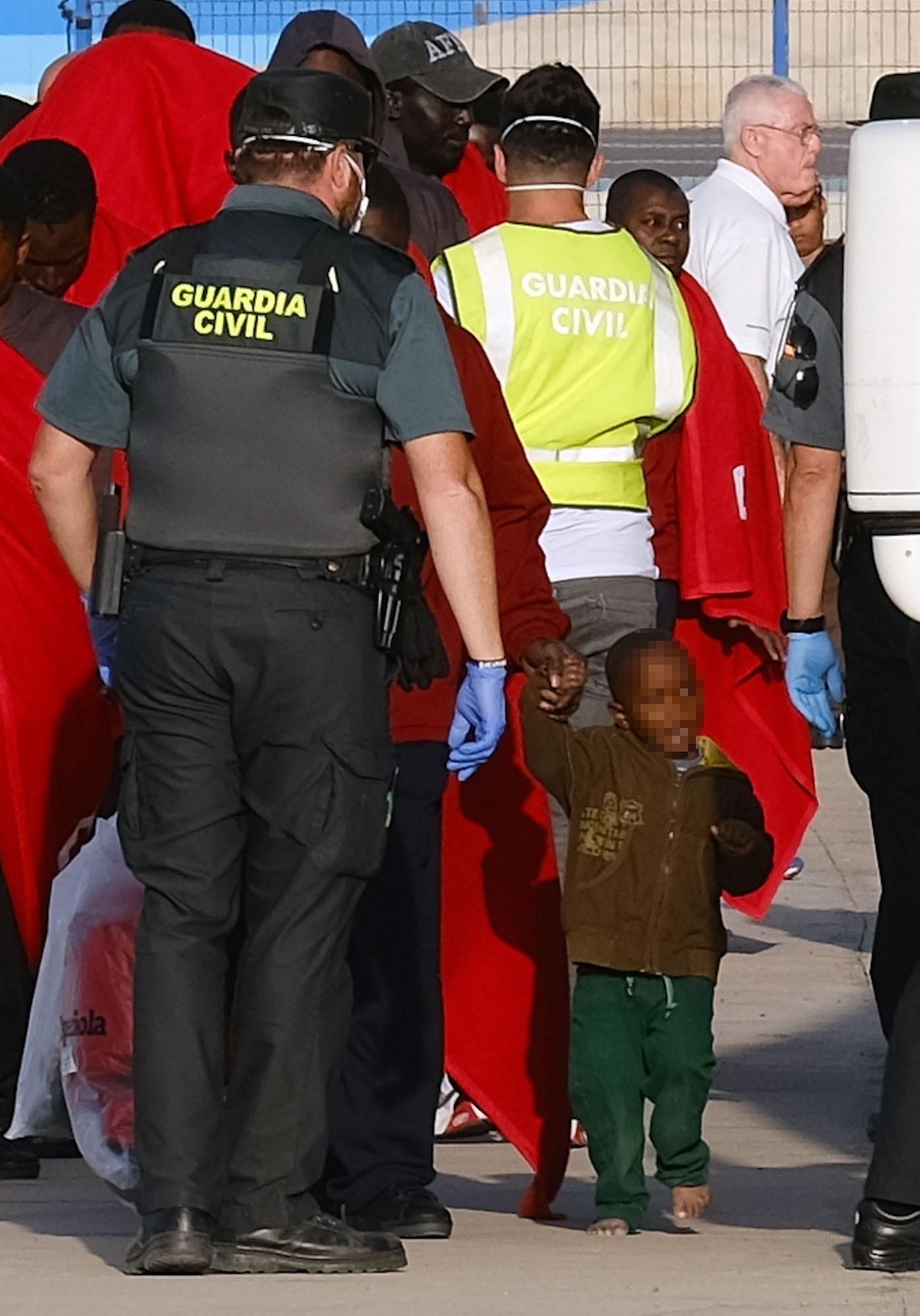 Miembros de la Guardia Civil ayudan a los 68 inmigrantes rescatados por Salvamento Marítimo a su llegada al muelle de Gran Tarajal (Fuerteventura), este lunes.