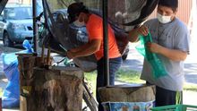 Dos hombres con tapabocas preparan el viernes 29 de mayo hoja de coca "machucada", en Santa Cruz (Bolivia). El negocio cayó como muchos otros al tener que quedarse la gente en casa por la pandemia del coronavirus, pero la venta de hoja de coca "machucada", como se conoce en Bolivia, también espera recuperarse poco a poco.