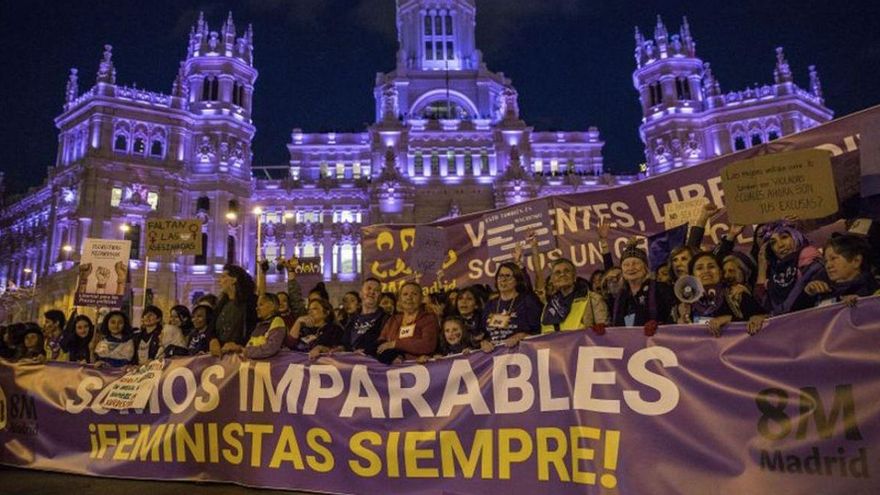 El edificio del Ayuntamiento de Madrid, iluminado de violeta, contempla el paso de la cabecera de la manifestación del 8M 2019