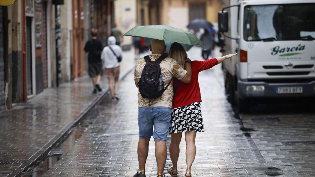Varias personas se protegen de la lluvia.