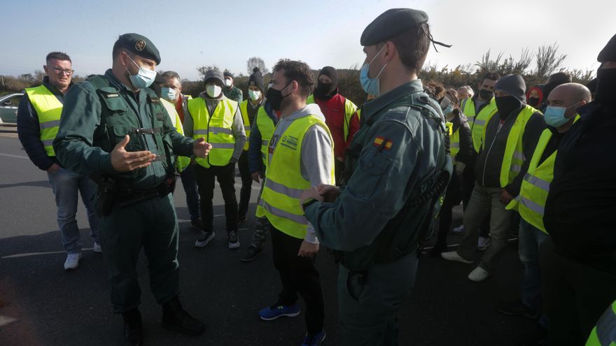 Dos agentes de la Guardia Civil hablan con los miembros de un piquete que han cortado la A-6 en ambos sentidos a la altura de Guitiriz, en Lugo