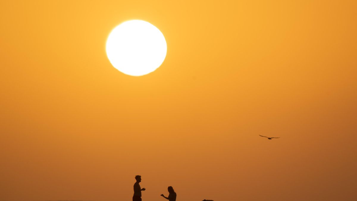 Dos personas en la playa de La Concha, en el municipio de La Oliva, en Fuerteventura, en una jornada en la que comienza a encaminarse a un episodio de calor extremo en los próximos días. EFE/Carlos de Saá