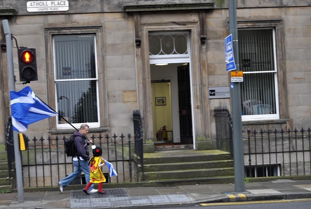 Un padre y su hijo recorren el centro de Edimburgo bandera escocesa en mano / Maruxa Ruiz del Árbol