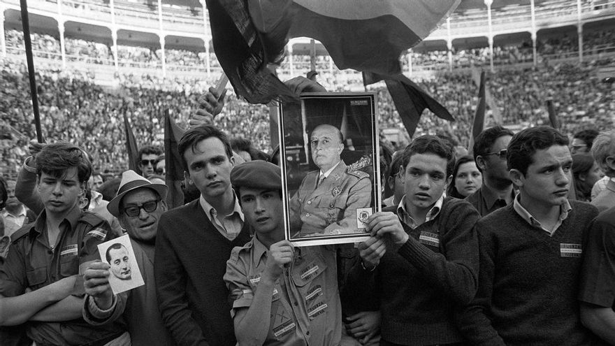 Unos jóvenes muestran retratos de Francisco Franco y de José Antonio Primo de Rivera, durante el mitin de Fuerza Nueva en Las Ventas en 1977.