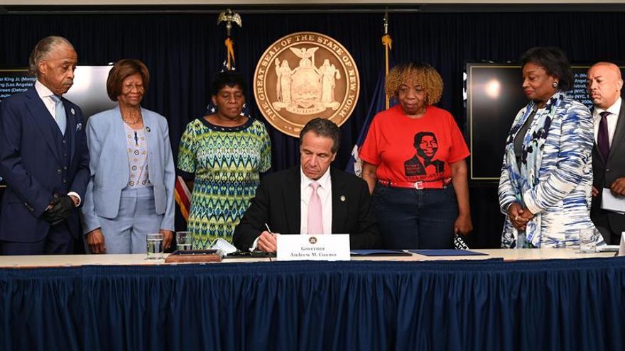 Fotografía cedida por la Gobernación de Nueva York donde aparece su gobernador, Andrew Cuomo (c), firmando una ley ejecutiva acompañado (i-d) del reverendo Al Sharpton; la presidenta de la Asociación Nacional para el Progreso de las Personas de Color (NAACP), Hazel N. Dukes; la líder demócrata del senado neoyorquino, Andrea Stewart-Cousins; las activistas Gwen Carr y Valerie Bell, y el presidente de la asamblea estatal, Carl Heastie, durante su rueda de prensa diaria ofrecida este viernes en Nueva York (EE.UU).