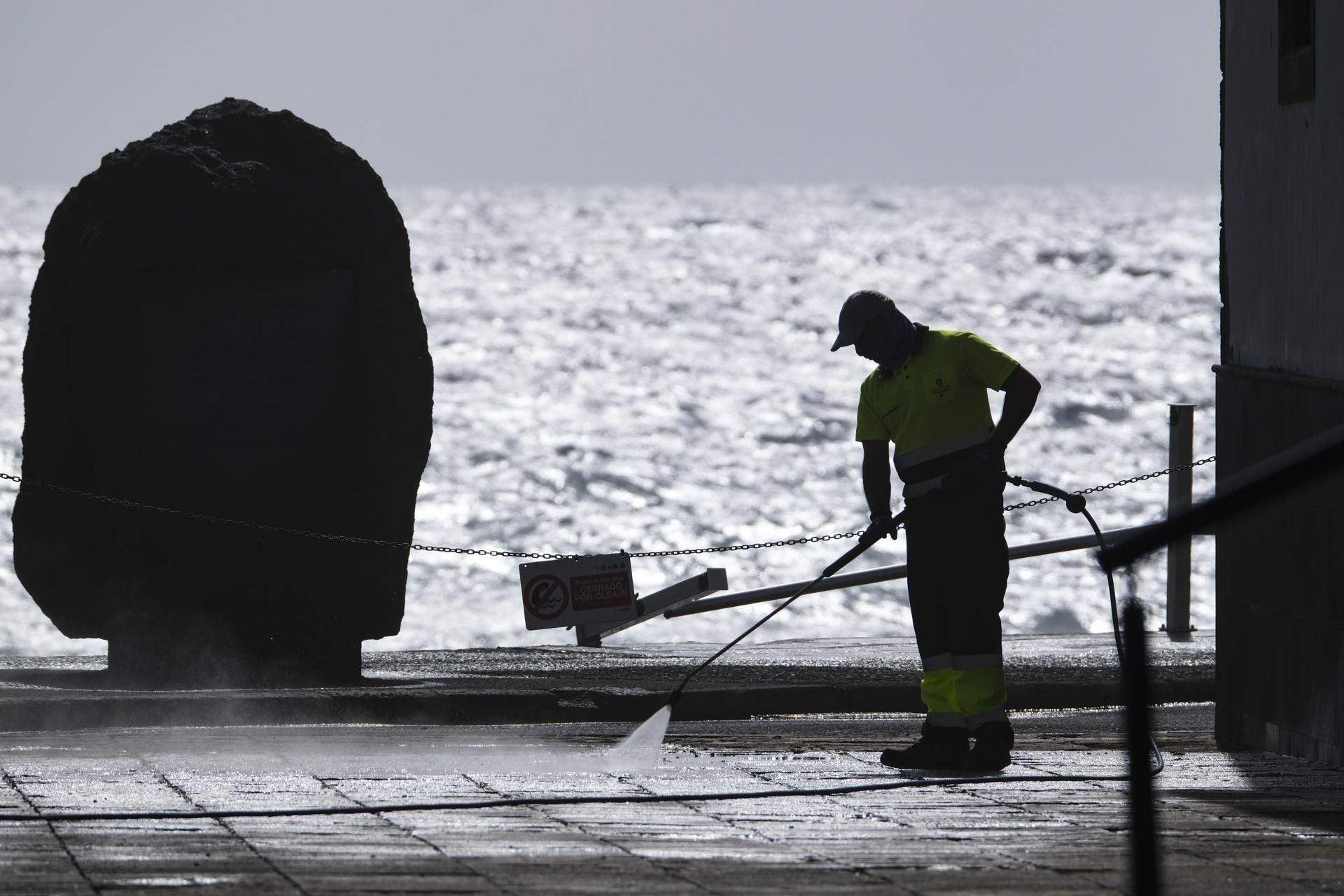Un operario limpia del destrozos del mar junto a la plaza de la Virgen de Candelaria.