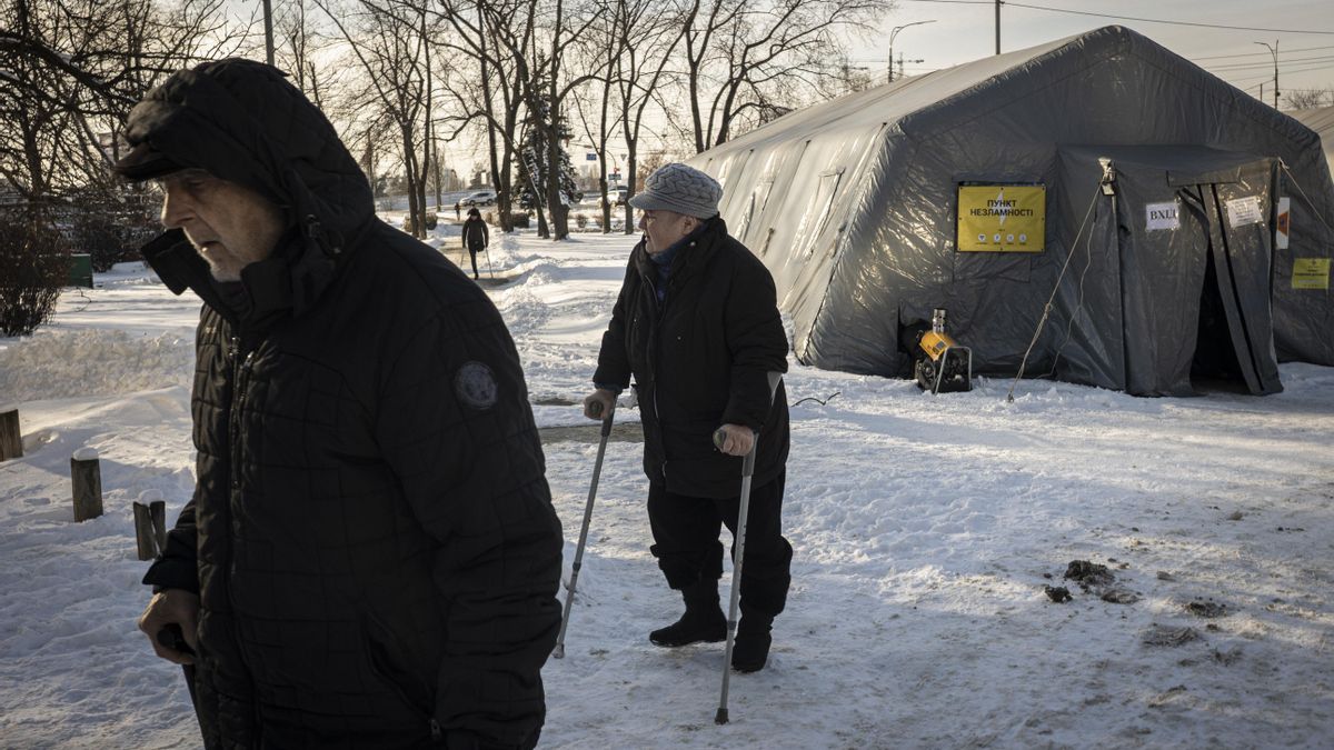 Dos ancianos con movilidad reducida vuelven a su casa tras calentarse en una tienda instalada por el Gobierno para hacer frente a los cortes de energía en Kiev.