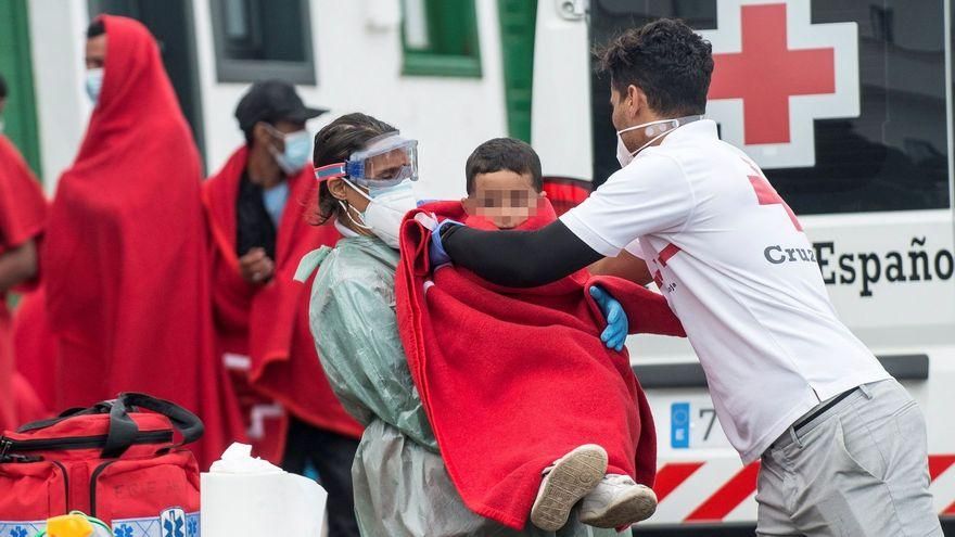 Un voluntario de la Cruz Roja abriga con una manta a uno de los niños que han llegado a las costas isleñas después de atravesar la ruta migratoria.