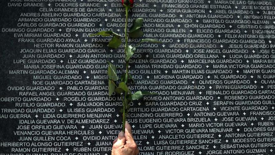 Una mujer coloca una rosa sobre un mural para honrar la memoria de las personas asesinadas y desparecidas durante la guerra civil salvadoreña este viernes, en el marco del Día Internacional de las Víctimas de Desapariciones Forzadas, en San Salvador (El Salvador).