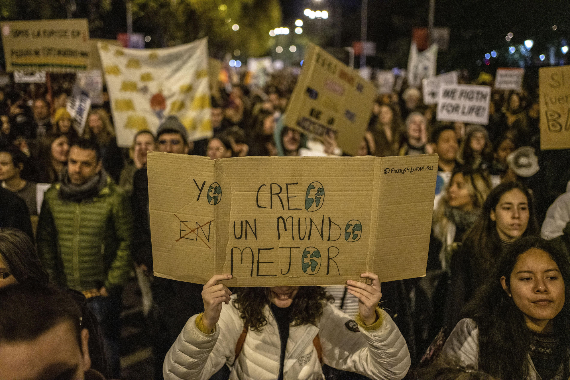 Una manifestante sostiene una pancarta que reza "Yo creo un mundo mejor"
