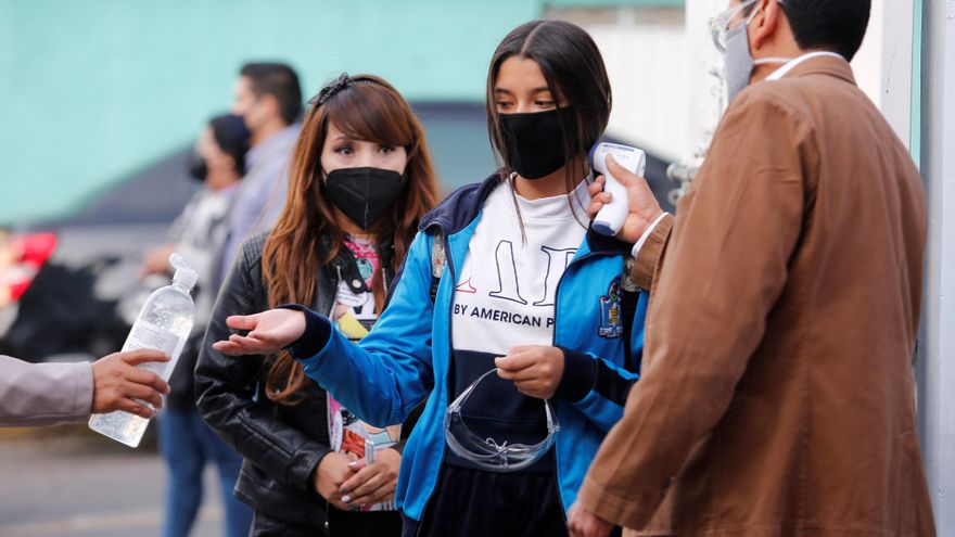 Estudiantes de nivel secundaria se toman la temperatura y se aplican gel antibacterial para ingresar a sus aulas en una escuela de Ciudad de México. EFE/Carlos Ramírez/Archivo