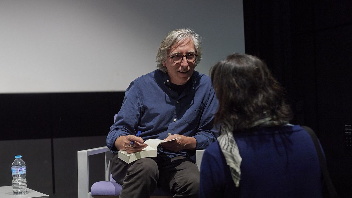 Trueba firma su libro a un asistente a la charla.