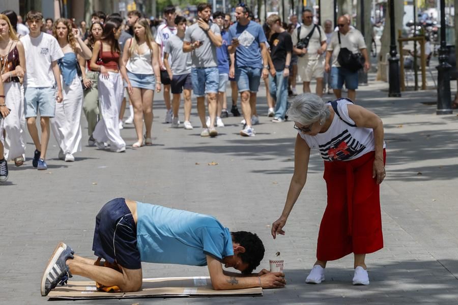 Un joven pide limosna entre turistas en el Passeig de Gràcia
