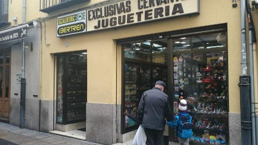 Un abuelo y su nieto se detienen a mirar el escaparate de Exclusivas Cervantes Juguetería.