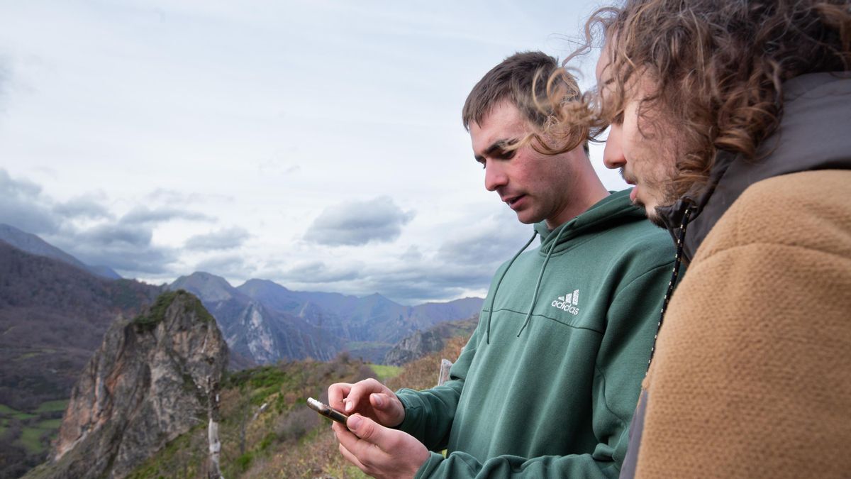 Pablo Riesgo junto a Emilio Tereñes observando el teléfono móvil con el que controlan el rebaño de cabras