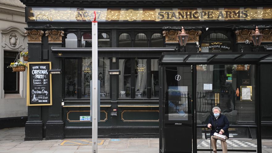 Una mujer espera el autobús en una parada situada delante de un pub en Londres. EFE/EPA/NEIL HALL