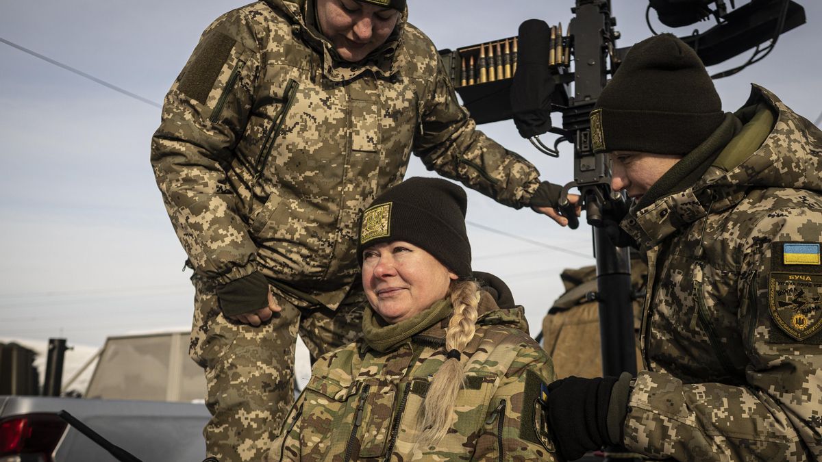 Tres de las integrantes de Las Brujas de Bucha junto a la ametralladora que utilizan para derribar drones.