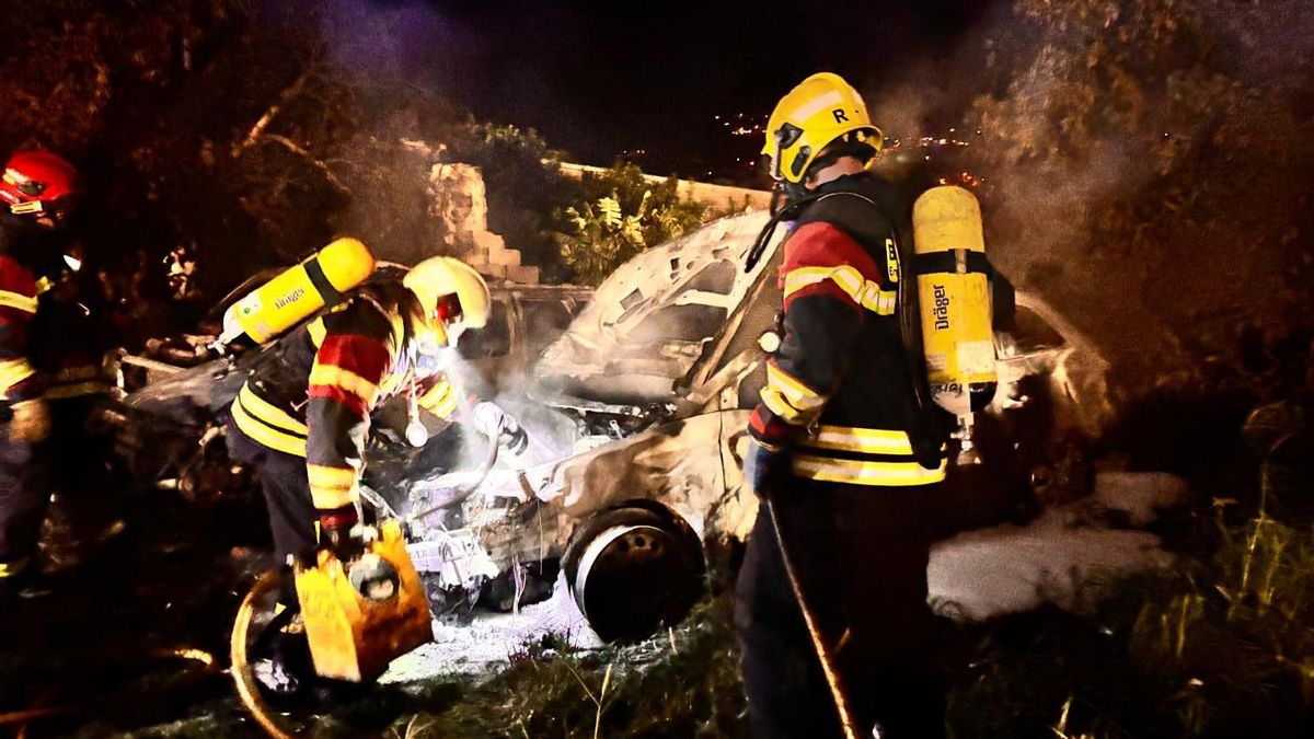 Tres bomberos apagando el fuego en los vehículos.