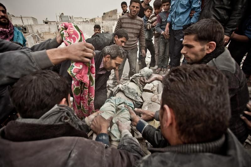 Un grupo de personas recadta el cuerpo de una niña de 6 años entre los escobrosn de una de las viviendas del barrios de Tariq Al AbaUn misil Scud se estrella en el barrio de Tariq Al Bab./Pablo Tosco/Oxfam Intermón