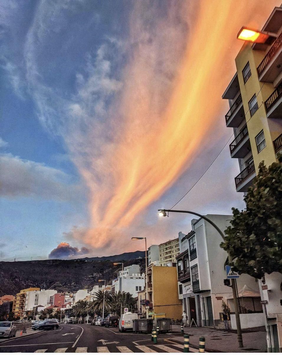 En la imagen, la nube de ceniza del volcán sobre el lomo de Cumbre Vieja y gran cirro iluminado por el sol, vistos desde Santa Cruz de La Palma.