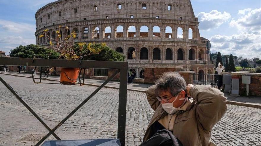 Un vecino se dispone a colocarse su mascarilla frente al Coliseo romano