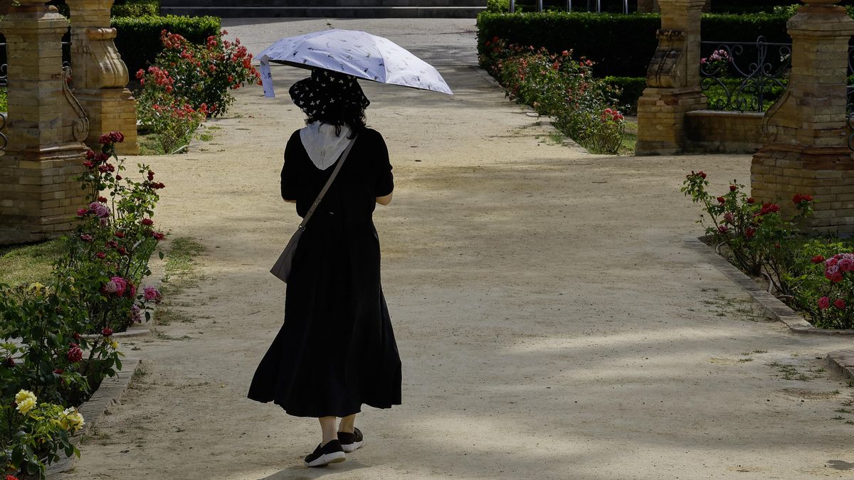 Una mujer protegiéndose del calor mientras camina por la calle