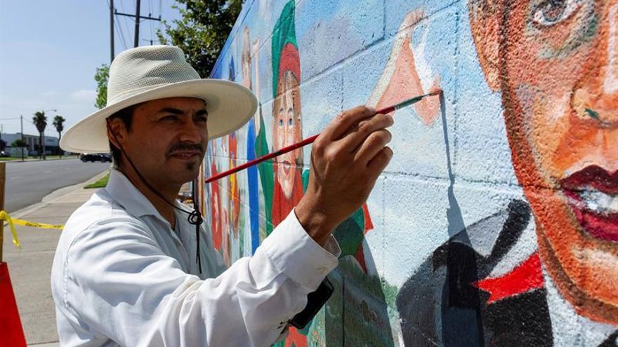 El artista Emigdio "Higgy" Vásquez trabaja el pasado 29 de agosto en la restauración del mural "Los Niños del Mundo", pintado en 1994 por su padre Emigdio Vásquez (1939-2014) en un pared del parque Lemon en la ciudad de Fullerton, California.