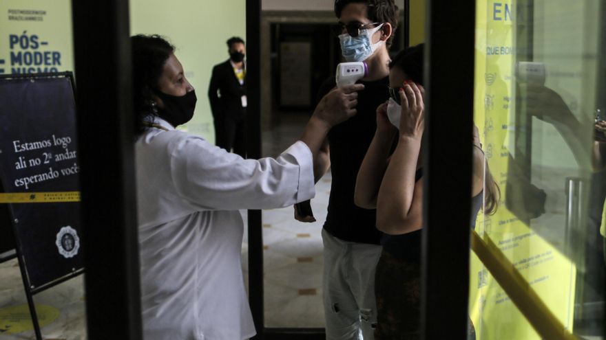 Una mujer toma la temperatura a visitantes del Centro Cultural Banco do Brasil hoy, en Río de Janeiro (Brasil). EFE/Antonio Lacerda