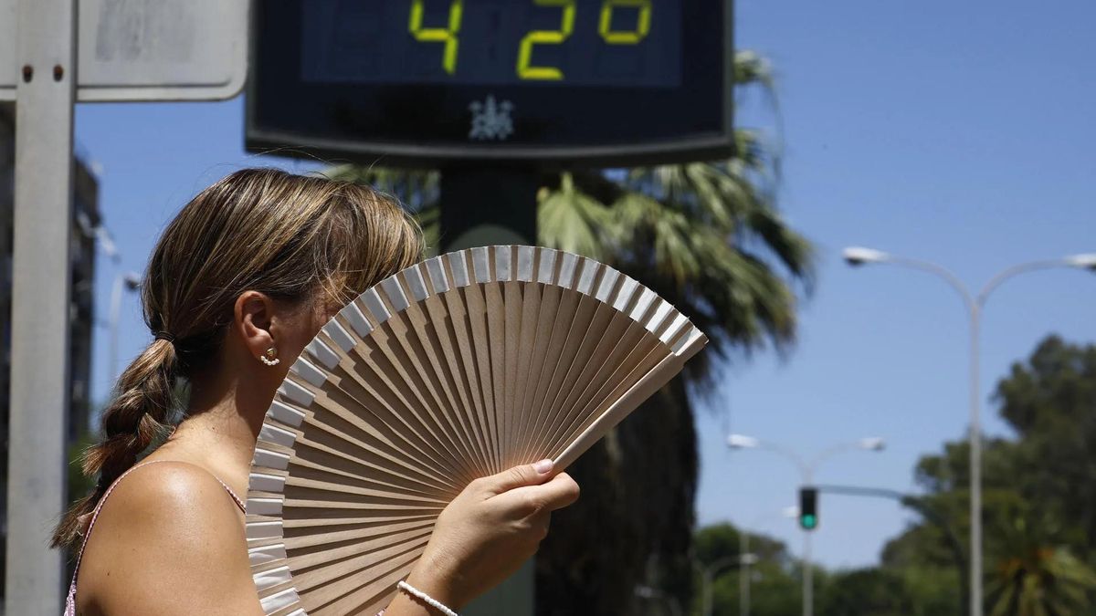 Una mujer se abanica mientras pasa por un termómetro de calle que marca 42 grados en Córdoba.