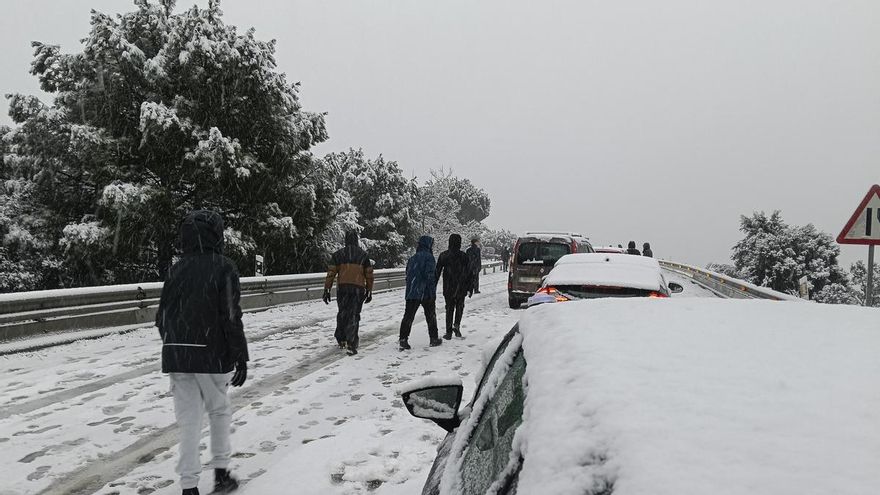 Una persona camina junto a varios vehículos en la carretera M-519 a la altura de Galapagar, este miércoles.