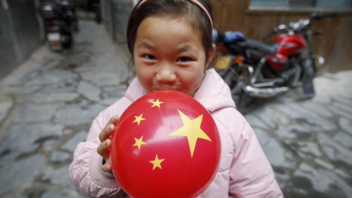 Una niña pequeña sostiene en sus manos una pelota con los colores de la bandera de China